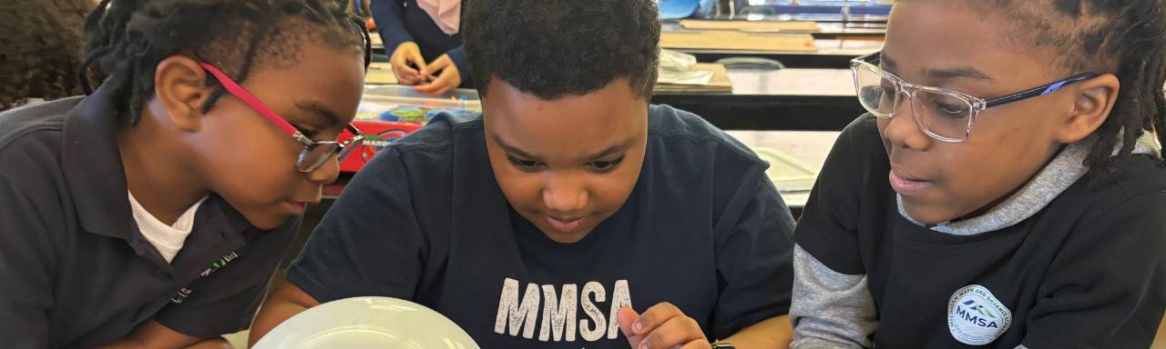 Three elementary students work together on a science project